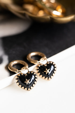 The Gold & Black Heart Huggie Hoop Earrings styled on a neutral background.