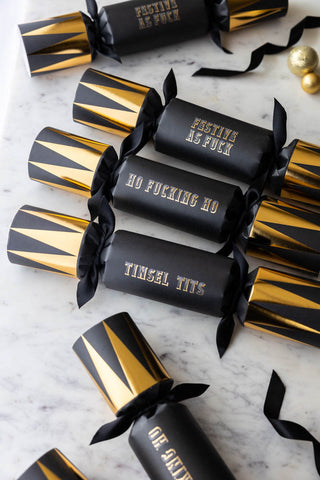 Set of 6 black and gold sweary crackers laid out on a table