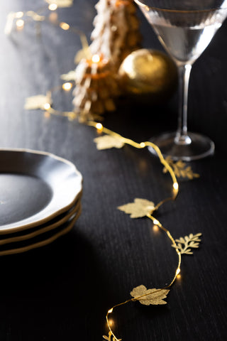 Beautiful golden leaf light chain fairy lights snaking down the centre of the table.