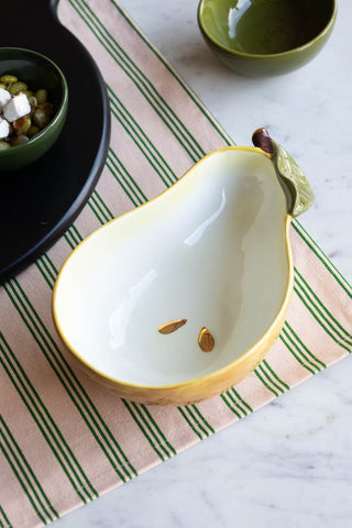 The Golden Pear Snack/Serving Bowl styled on a striped tablecloth with other serveware.