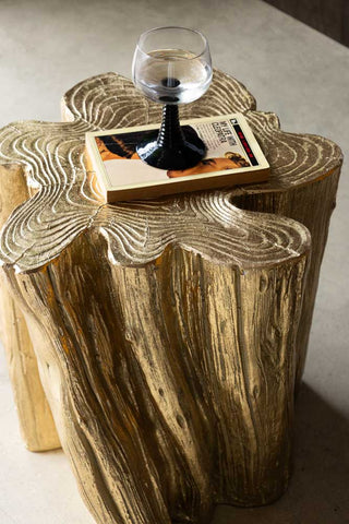 The Golden Tree Stump Small Side Table seen from above, with a book and a wine glass on.