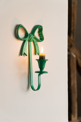 The Green Bow Wall-Mounted Candle Holder on a neutral wall, styled with a lit candle inside.