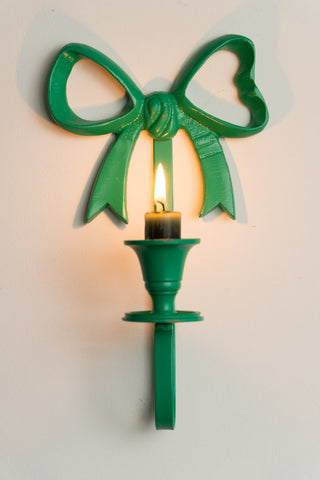 Close-up of the Green Bow Wall-Mounted Candle Holder on the wall with a lit candle inside.