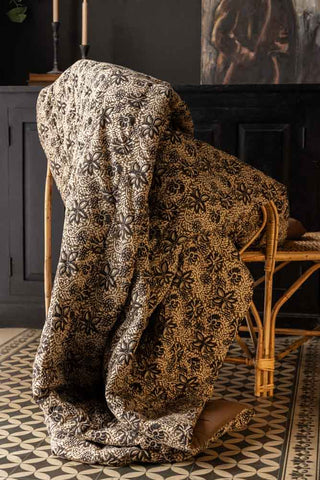 The Green Floral Quilt in King-Size styled draped on a wicker chair.