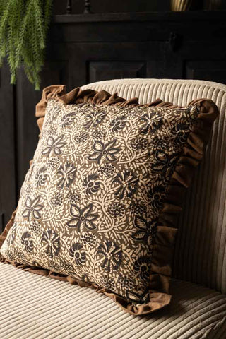 The Green Floral Ruffle Edge Cushion styled on a chair.