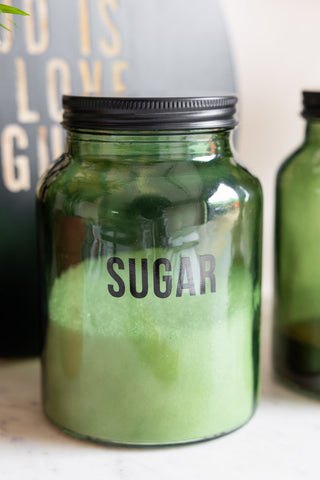 Close-up of the Green Glass Storage Jar With Black Lid - Sugar, filled with sugar inside.