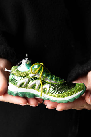 The Green Trainer Christmas Tree Decoration being held in a model's hands.