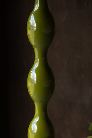 Close-up of the wavy detail of the Green Wavy Retro Floor Light, in front of a dark wall.