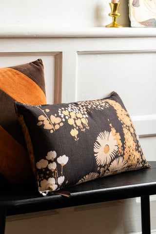 The HKLiving Dark Florals Cotton Cushion styled on a black bench with another cushion.