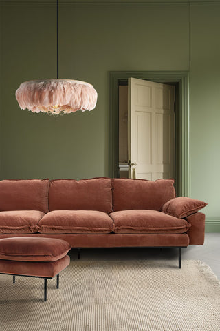 The HKliving Retro 4 Seater Sofa in Magnolia Velvet styled with the matching footstool in a living room, with a rug and feather pendant light.