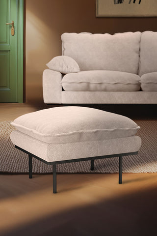 The HKliving Retro Footstool in taupe Boucle styled on a rug in a living room in front of the matching sofa.