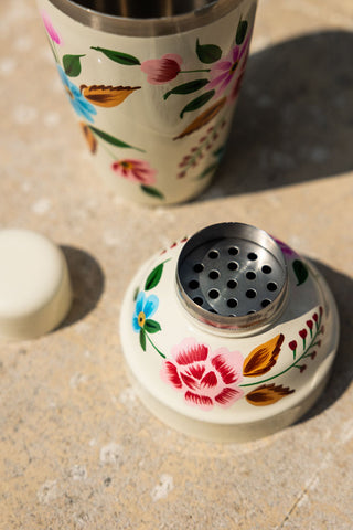 The Hand Painted Floral Detail Cocktail Shaker displayed in its separate components on an outdoor table.