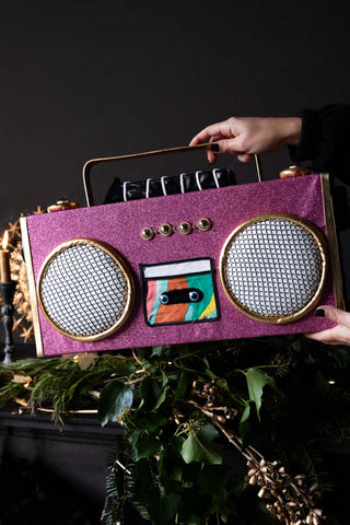 The Handmade Candy Pink Boom Box Decoration being held in a model's hands with some decorations in the background.