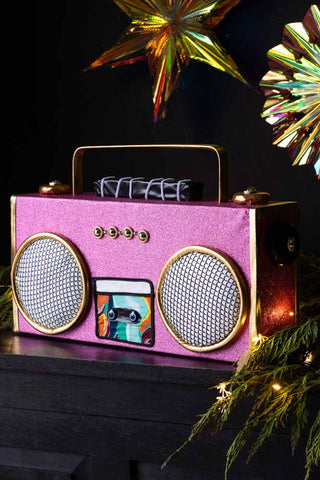 The Handmade Candy Pink Boom Box Decoration displayed on a black sideboard with some greenery, lights and Christmas decorations.