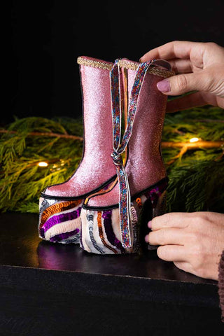 The Handmade Groovy Spiral Platforms Decoration styled on a black sideboard with some greenery and lights, being held by a model's hands.