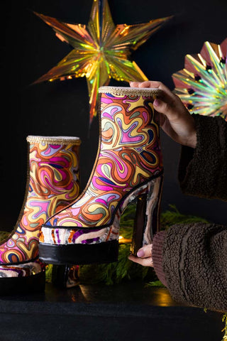 The Handmade Groovy Platform Boots Decoration being held in a model's hand's, with another one and some Christmas decorations in the background.