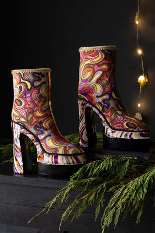 Two of the Handmade Groovy Platform Boots Decorations styled together on a black sideboard with some greenery and fairy lights.