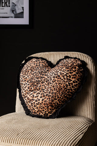 The Heart Leopard Print Velvet Ruffle Cushion displayed on a chair.