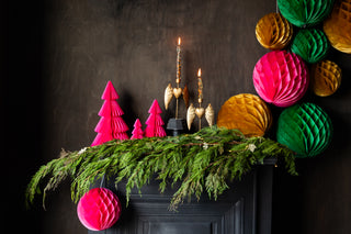 An amazing and beautiful festive fireplace with honeycomb balls, christmas paper trees and candlesticks.