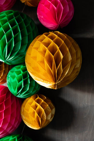 Lifestyle image of the Set Of 2 Gold Honeycomb Ball Decorations amongst other coloured honeycombs