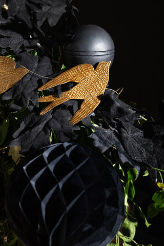 Image of the Pretty Gold Birds Garland hung on a black banister with black decorations.