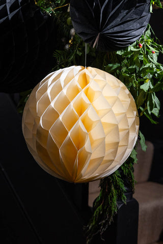 Close-up of the Set Of 2 Ivory Honeycomb Ball Decorations hung on a stair banister.