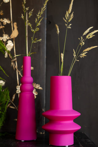 Two Hot Pink Vases styled together on a black sideboard, filled with flower stems.