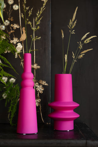 The two Hot Pink Vases styled with flower stems on a black sideboard.