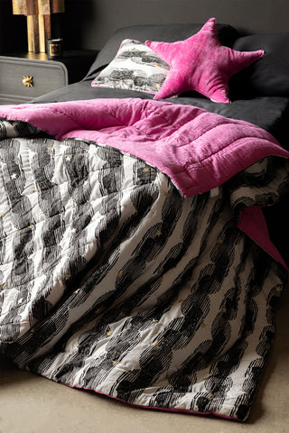 The Hot Pink & Gold Star Print Reversible Quilt in King-Size styled draped across the end of a bed.