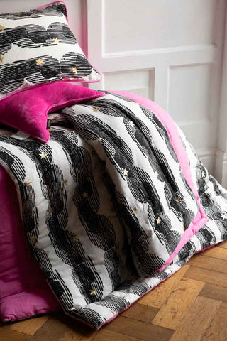 The Hot Pink & Gold Star Print Reversible Quilt in King-Size styled on a white panelled backdrop on a wooden floor.