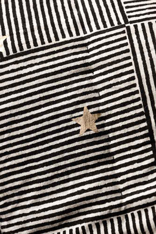 Detail shot of the stripes/star motifs on the Monochrome & Gold Star Detail Print Quilt in King-Size.