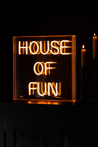 The House Of Fun Neon Light Box switched on and styled next to two lit candles.