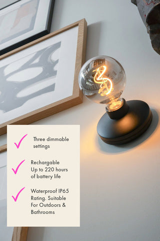 Black humble wall light with three ticks stating that the light is rechargable, waterproof and has three dimmable settings