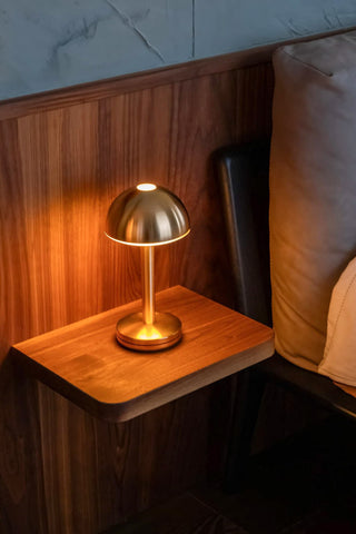 The Humble - Domed Cable-Free Mood Lighting Lighting in Gold displayed on a bedside table.