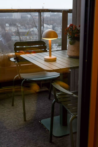 The Humble - Domed Cable-Free Mood Lighting Lighting in Off White displayed on a small dining table with a plant.