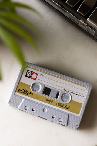 The I Made You A Mix Tape Cassette Tape Storage Tin seen from above, styled on a white marble surface with another tin and a plant.