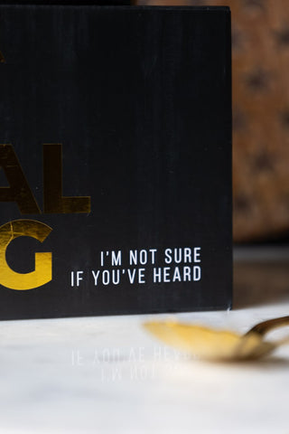 Detail shot of the text on the box of the I'm Kind Of A Big Deal Mug, displayed on a marble table with a spoon.