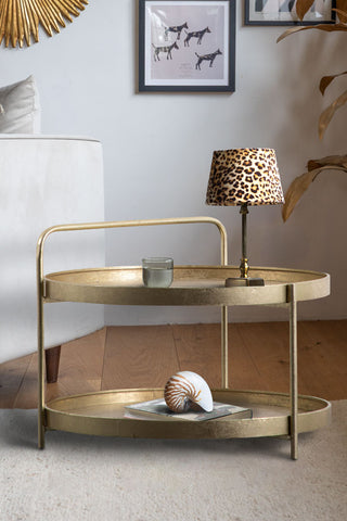 The Industrial Style Two-Tier Coffee Table Gold styled with various accessories on, displayed next to a sofa in a living room.