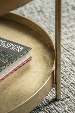 Close-up of the bottom tier of the Industrial Style Two-Tier Coffee Table Gold, styled with a book on and displayed on a rug.