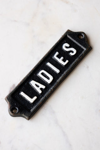 The Ladies Door Hanging Sign displayed on a white marble surface.