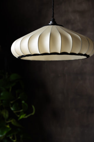 The Lantern Style Flush Easyfit Light Shade styled in front of a dark wall and a plant.