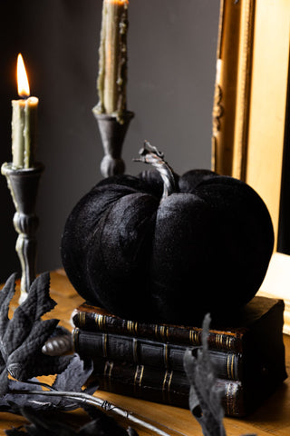 The Large Black Velvet Pumpkin displayed on books with maple leaf garland, candles and gold frame.