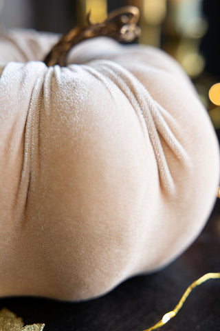 Close-up of the Large Cream Velvet Pumpkin on a dark wooden surface with some fairy lights.