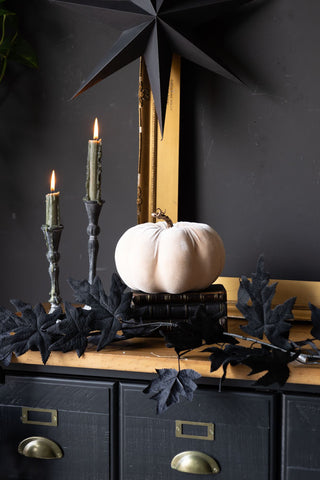 The Large Cream Velvet Pumpkin displayed on a wooden surface with books, maple garland and candle.