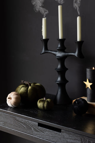 A dark room with the black candelabra with white candles.