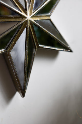 Close-up of the bottom of the Large Mirrored Star Wall Decoration on a white wall.