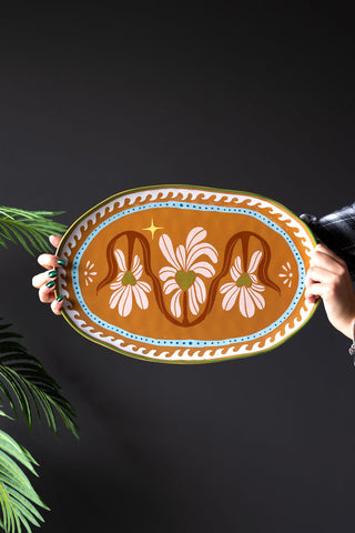 The Large Oval Plate With Hearts styled against a black background shown in someone's hands.