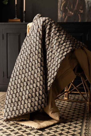 The Leaf Print Reversible Quilt in King-Size displayed draped across a chair.