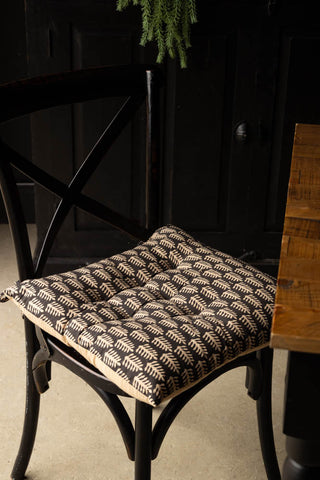 The Leaf Print Seat Cushion on a dining chair next to a table.