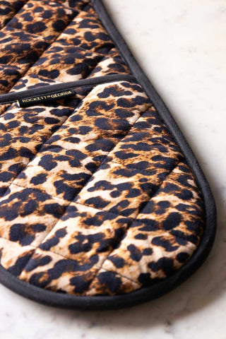 Detail shot of one end of the Luxury Leopard Print Oven Gloves, displayed on a white marble surface.